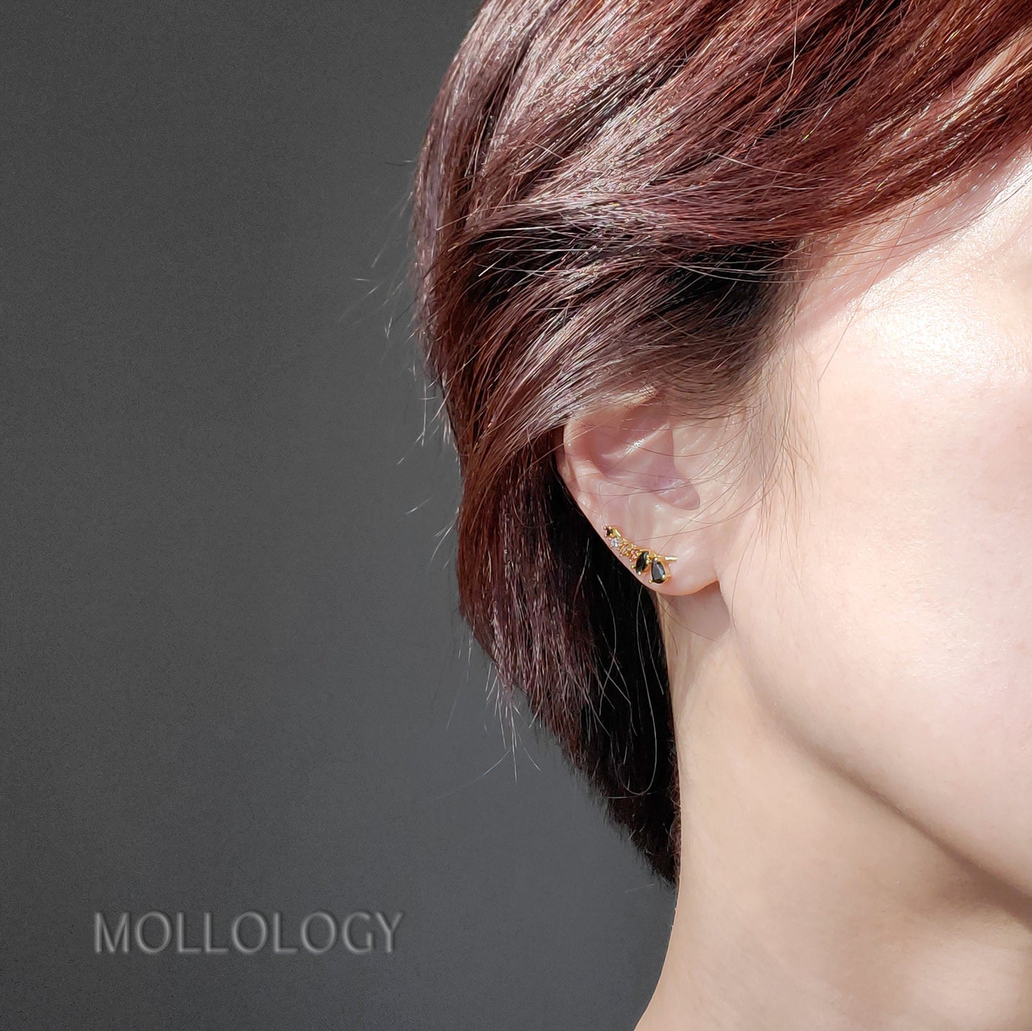 A pair of black onyx and rose quartz ear climbers placed on a white surface with the brand name 'MOLLOLOGY' visible in the background.