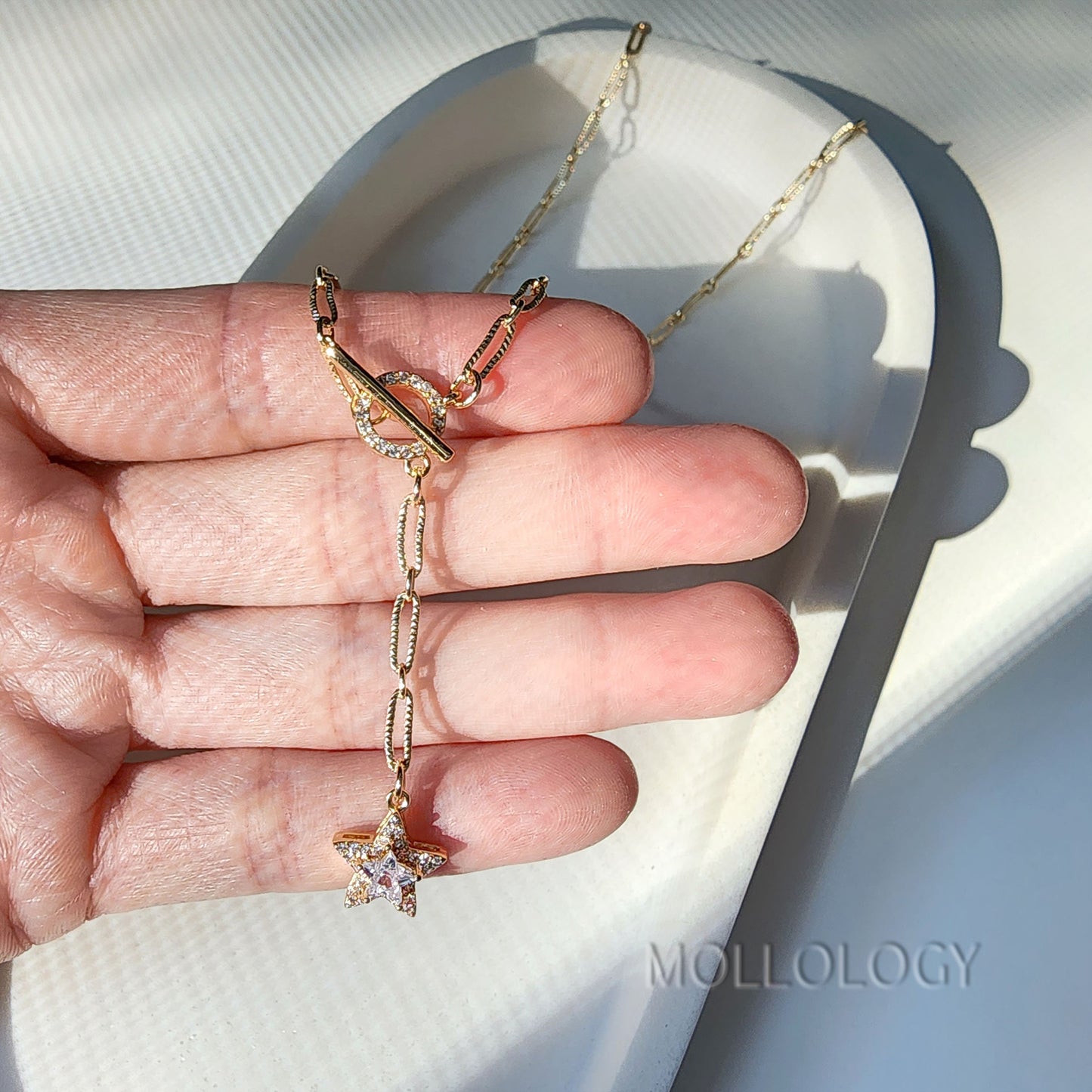 a gold chain link necklace with a star charm