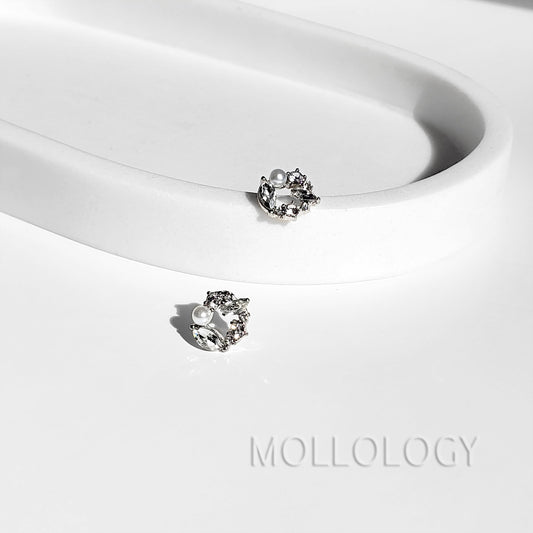 Pair of dainty pearl and cubic zirconia flower stud earrings displayed on a white curved tray.