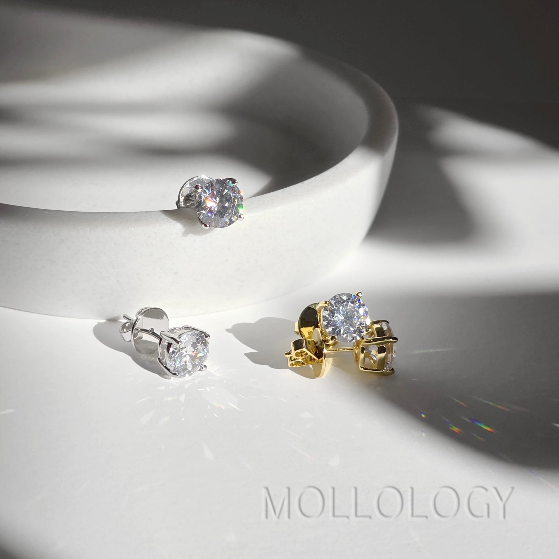 Gold and white gold CZ solitaire stud earrings together on white dish, mixed metal diamond-style studs