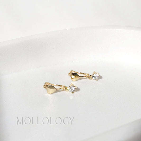 dainty gold heart huggie hoop earrings on white background
