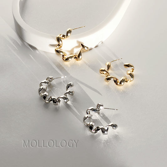 Three twisted hoop earrings displayed on a glossy white surface, including two gold-toned hoops and one silver-toned hoops, with the brand name MOLLOLOGY printed at the bottom left.