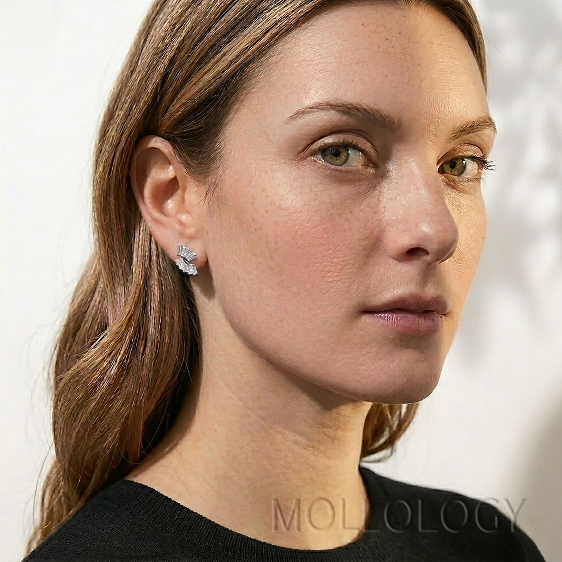 Model wearing dainty art deco baguette fan stud earrings with a geometric design.