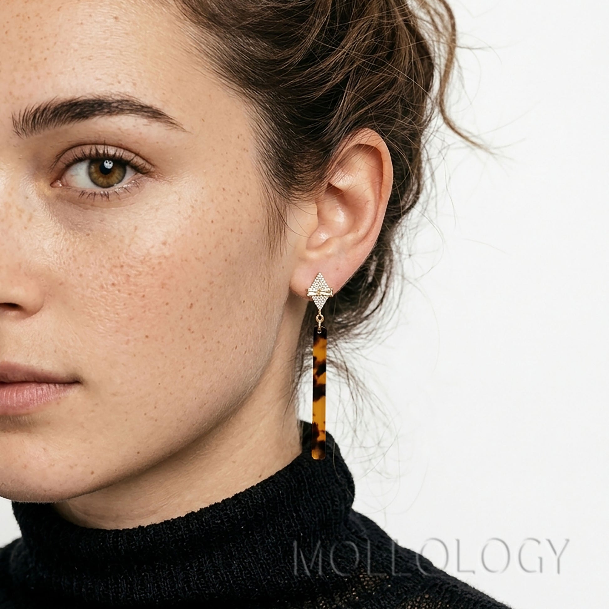Model wearing art deco tortoiseshell bar earrings with a sparkling geometric gold top.