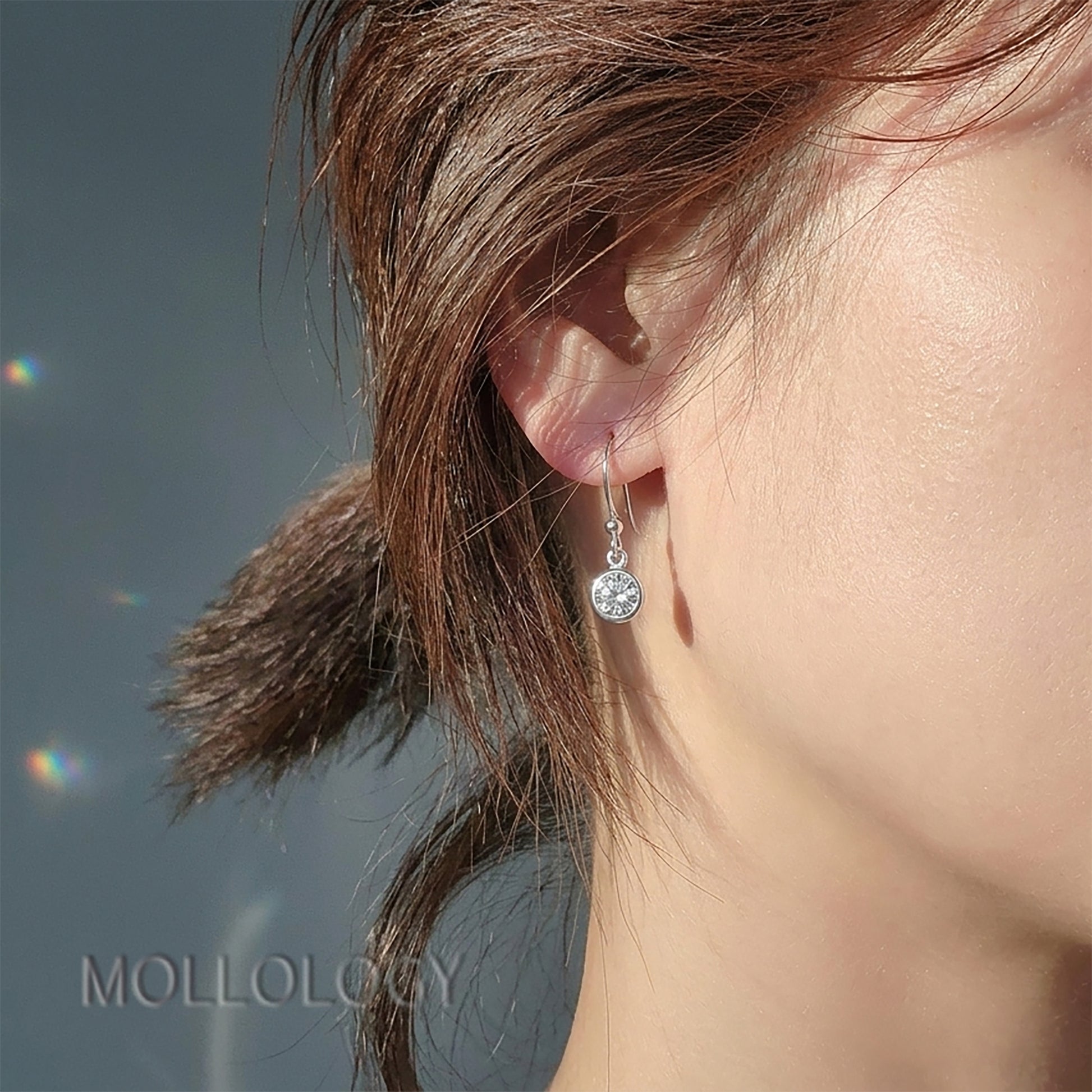 Silver bezel CZ drop earrings on ear, minimalist dainty dangle earring in natural sunlight