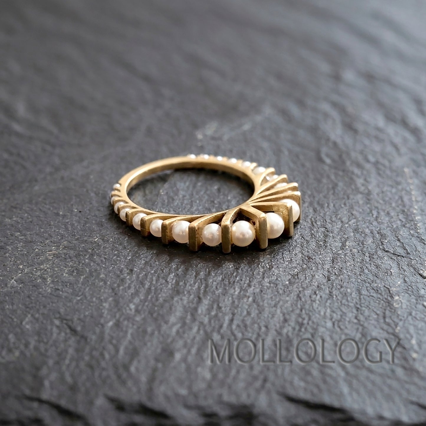 Art deco gold pearl ring on dark stone surface, 14k gold plated fan style band with small round imitation pearls in an arched design