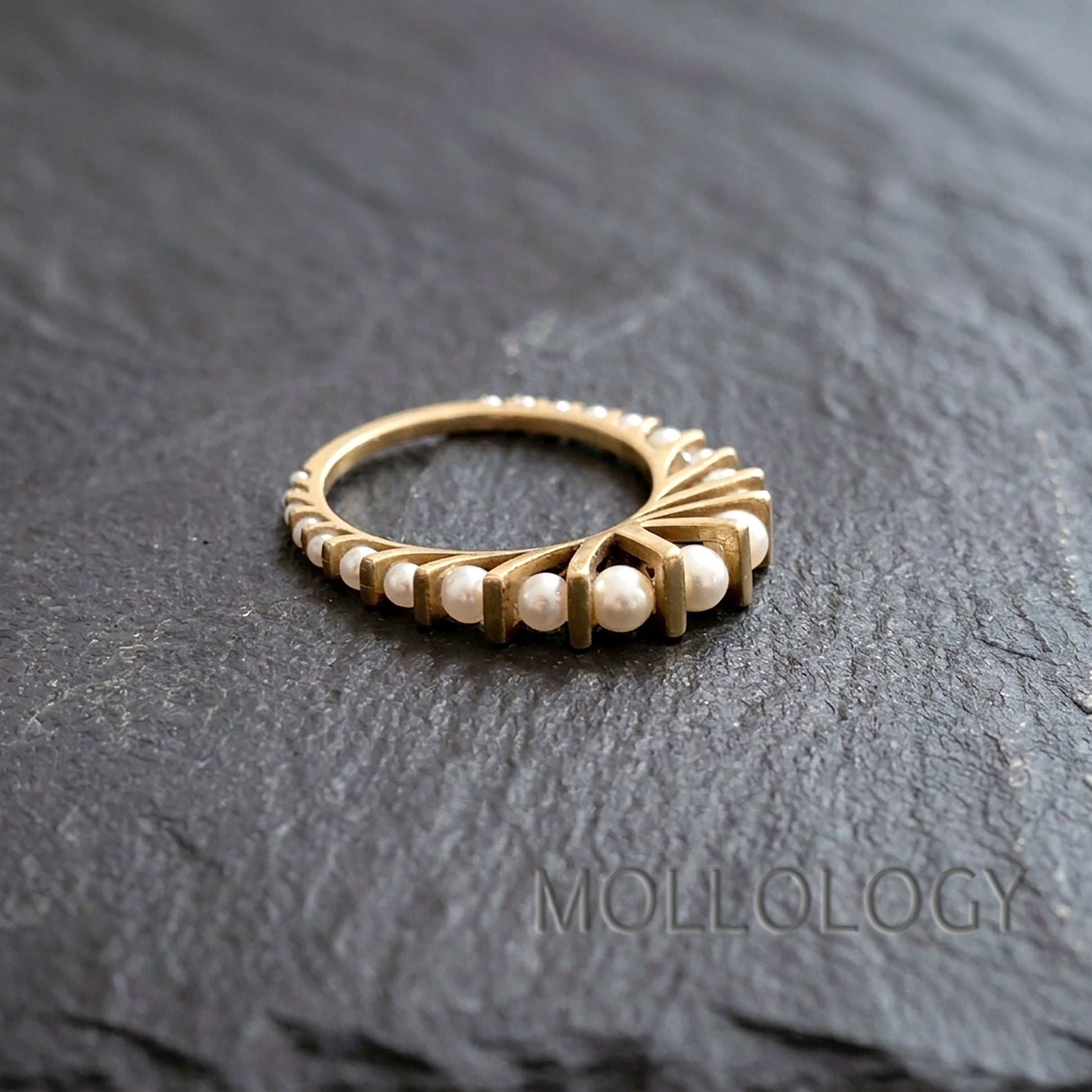 Art deco gold pearl ring on dark stone surface, 14k gold plated fan style band with small round imitation pearls in an arched design
