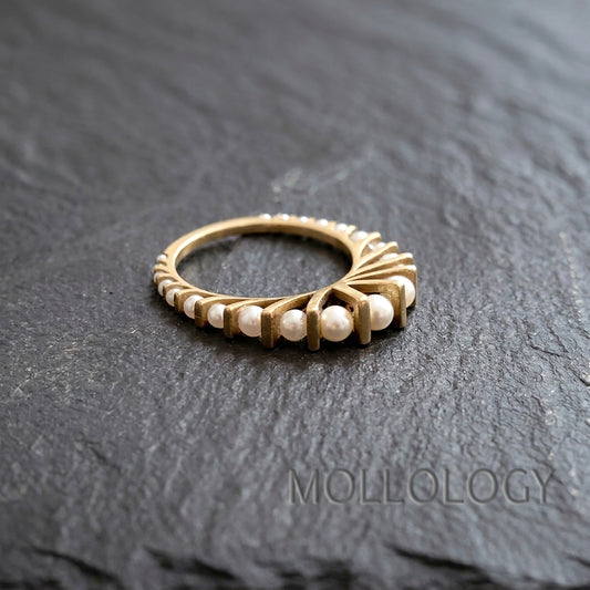 Art deco gold pearl ring on dark stone surface, 14k gold plated fan style band with small round imitation pearls in an arched design