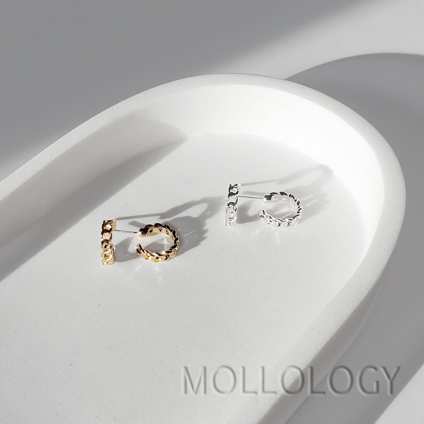 Gold and silver chainlink huggie earrings shown side by side on a white tray.