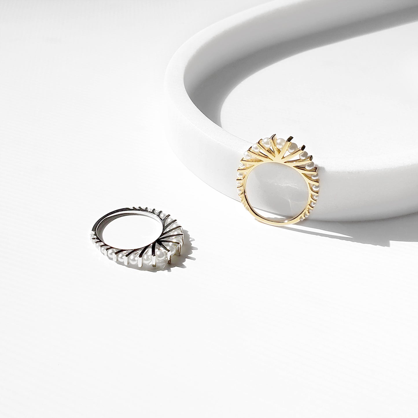 Bridal pearl ring in gold and silver on white tray, fan shaped band with pearls, dainty wedding stacking ring