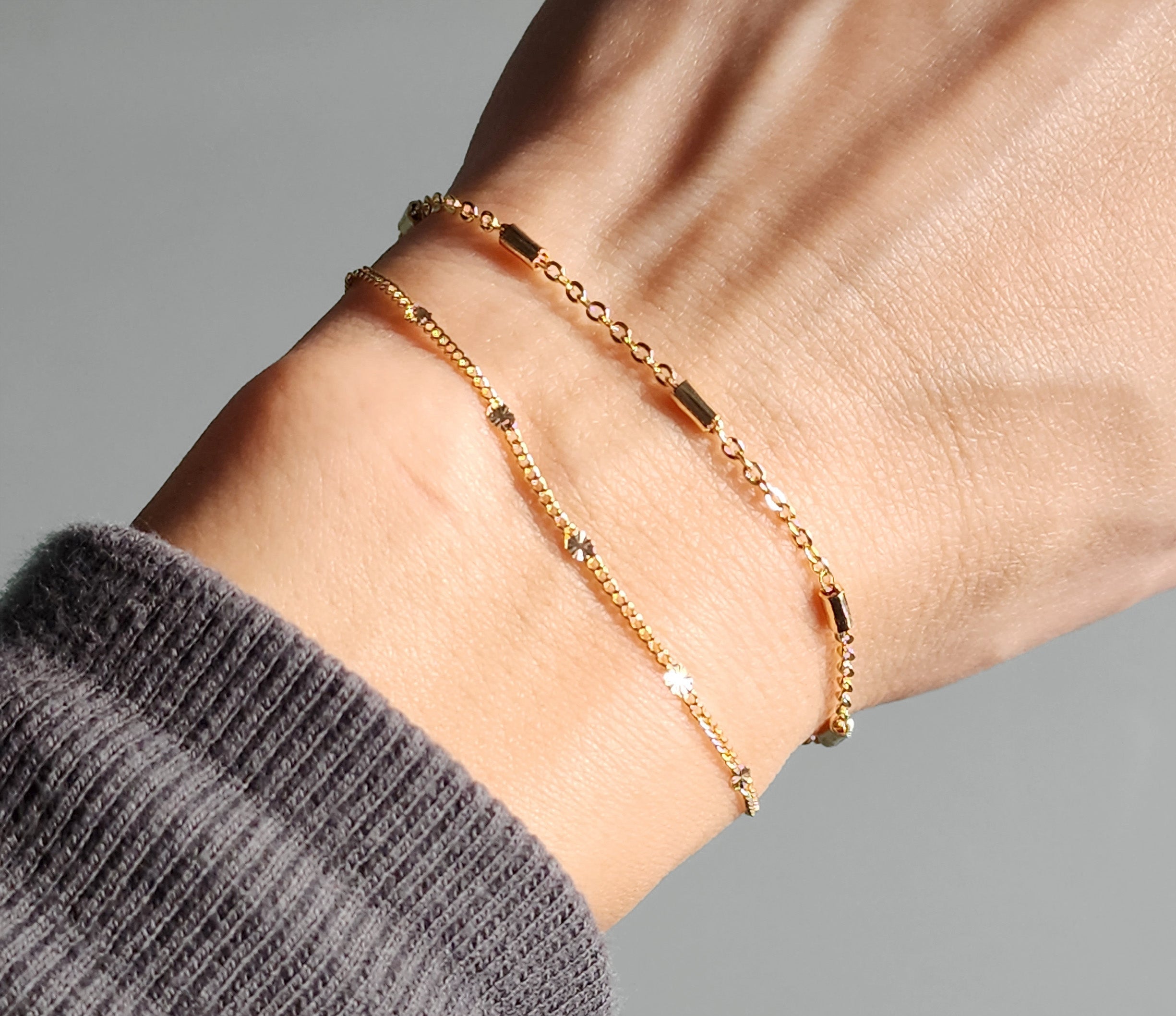 dainty gold bracelets on a model's hand