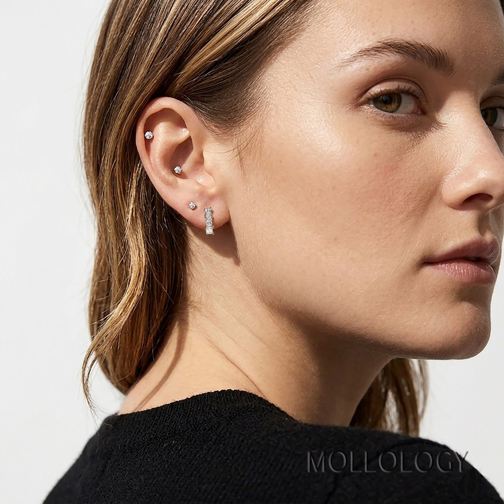 Gold baguette stud earrings worn on model with multiple piercings, minimalist sparkle earrings and ear stack jewelry by MOLLOLOGY.


