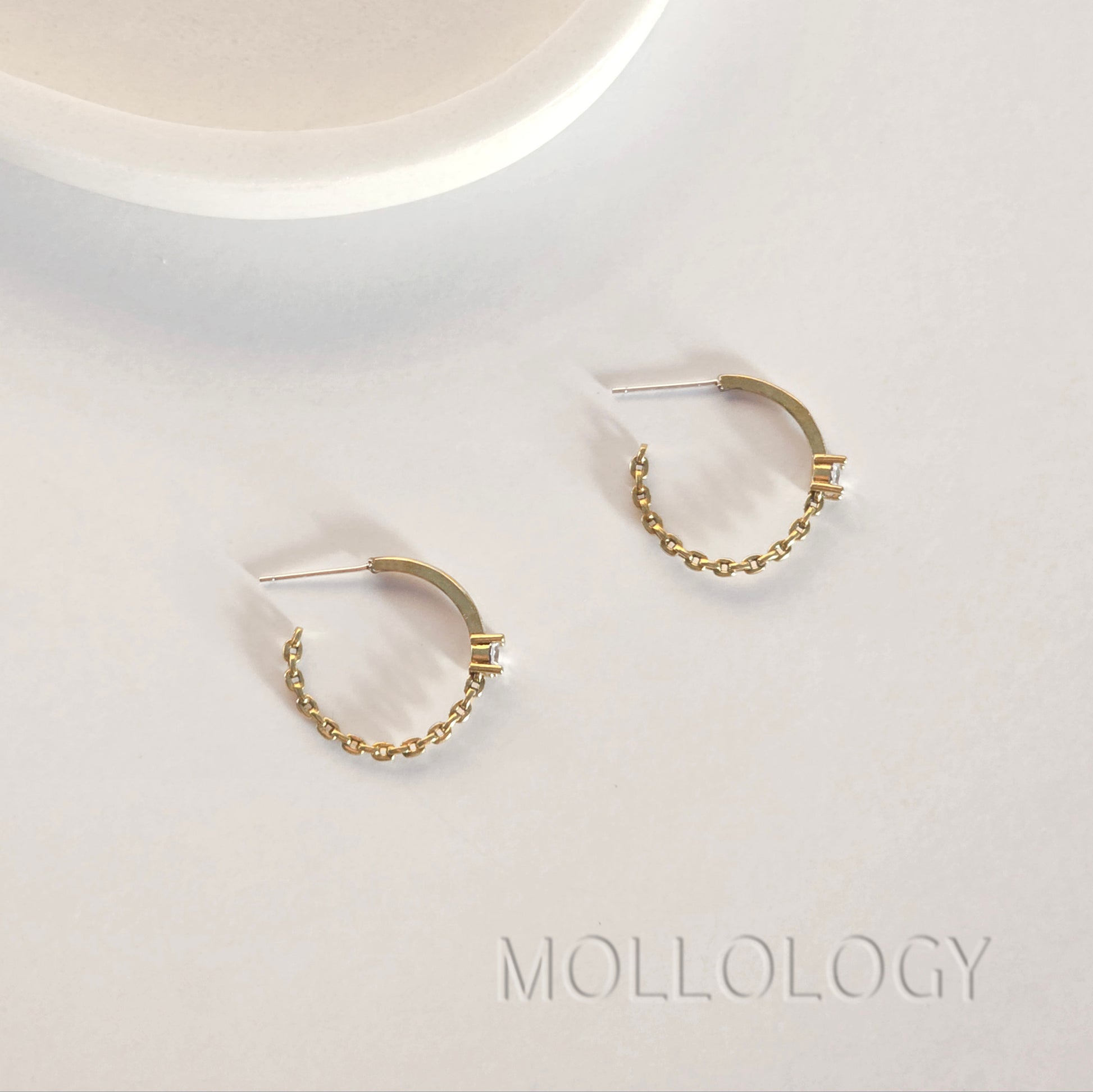 Gold chain hoop earrings with sparkling CZ held in hand, close up minimalist MOLLOLOGY jewelry detail shot.