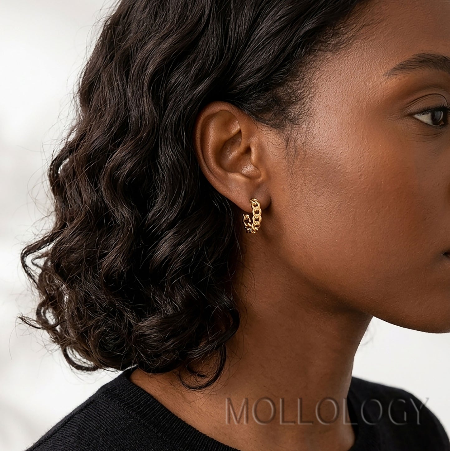 Model wearing dainty gold chainlink huggie earrings.