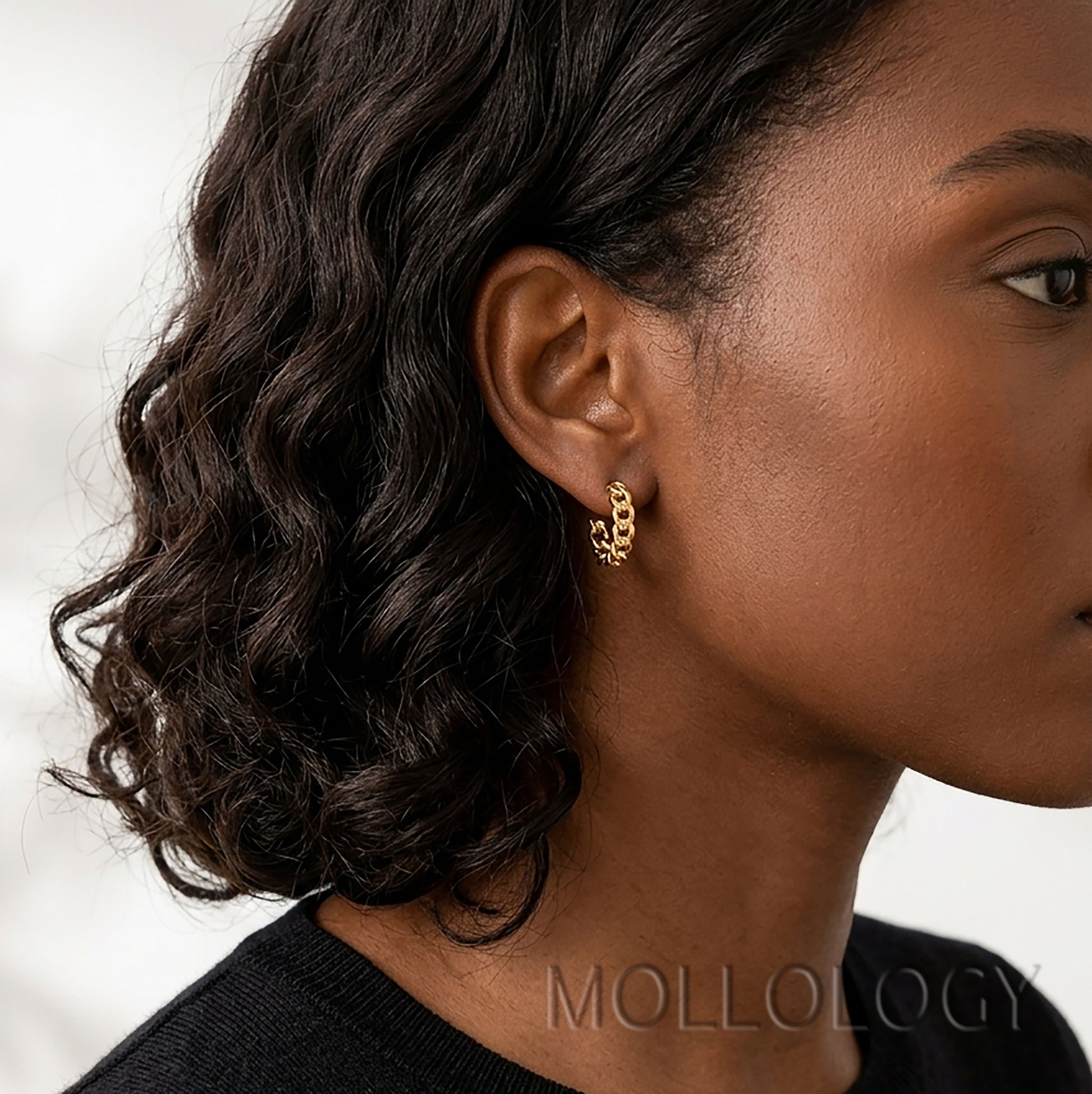 Model wearing dainty gold chainlink huggie earrings.