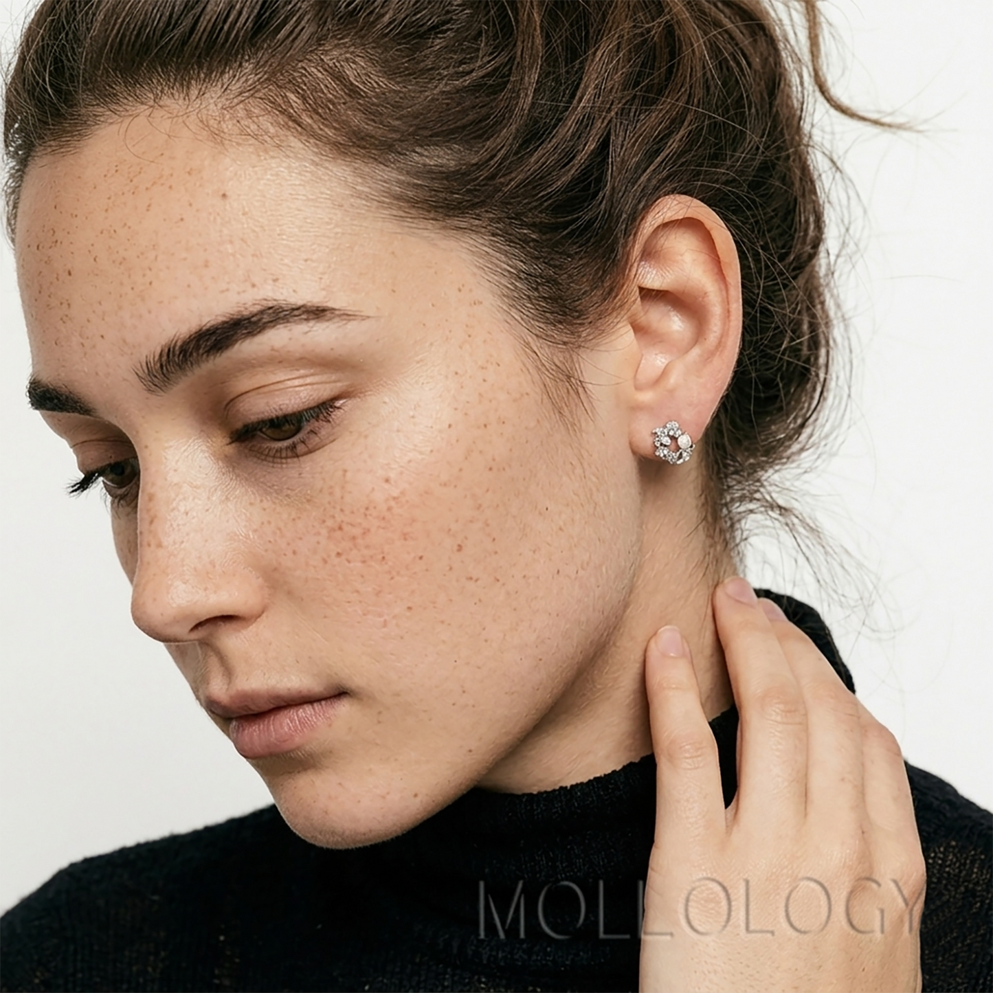 Close-up of a woman wearing dainty pearl and cubic zirconia flower stud earrings in a silver finish.
