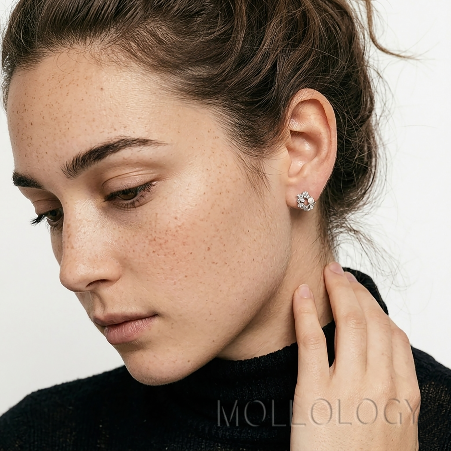 Close-up of a woman wearing dainty pearl and cubic zirconia flower stud earrings in a silver finish.