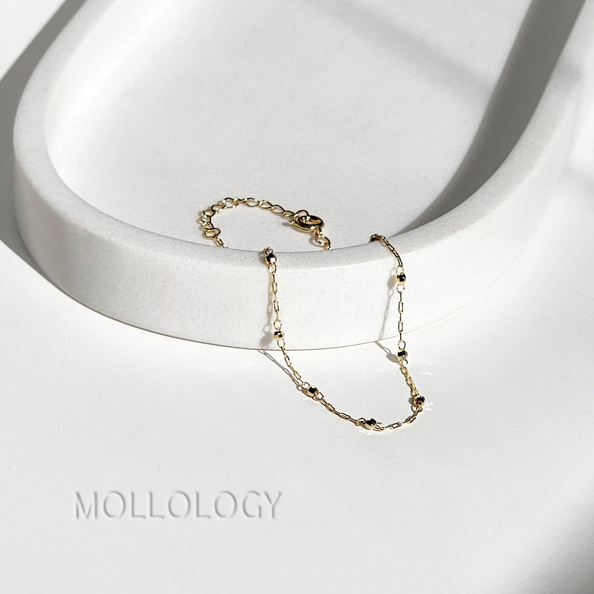 Detailed view of a 14K gold satellite bead chain bracelet with a polished finish and secure lobster clasp closure.