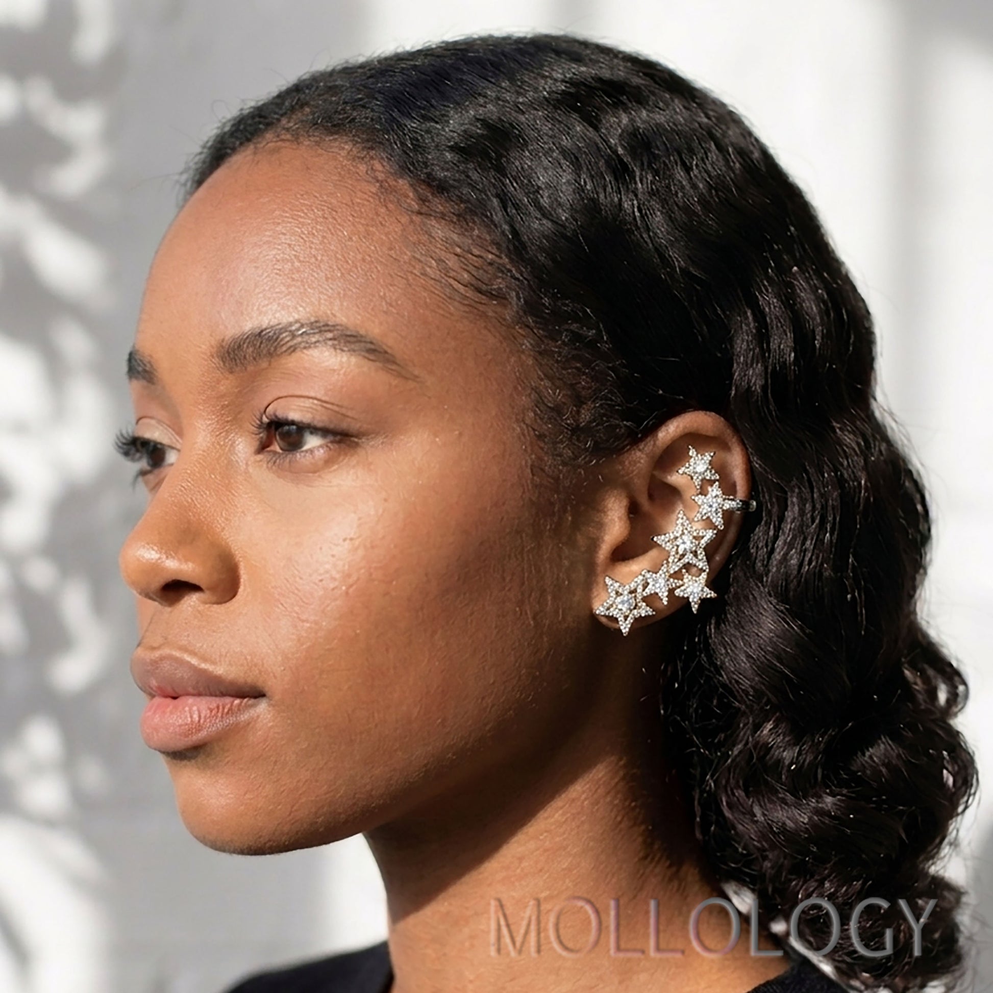 Model wearing silver star climber earrings with sparkling star shapes along the ear.