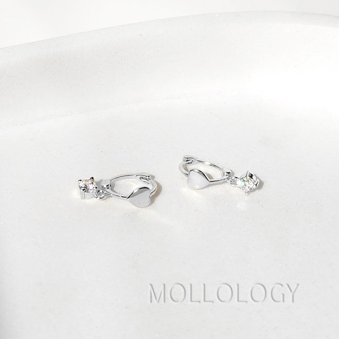 Close up of 4mm cubic zirconia heart charm on gold huggie hoop