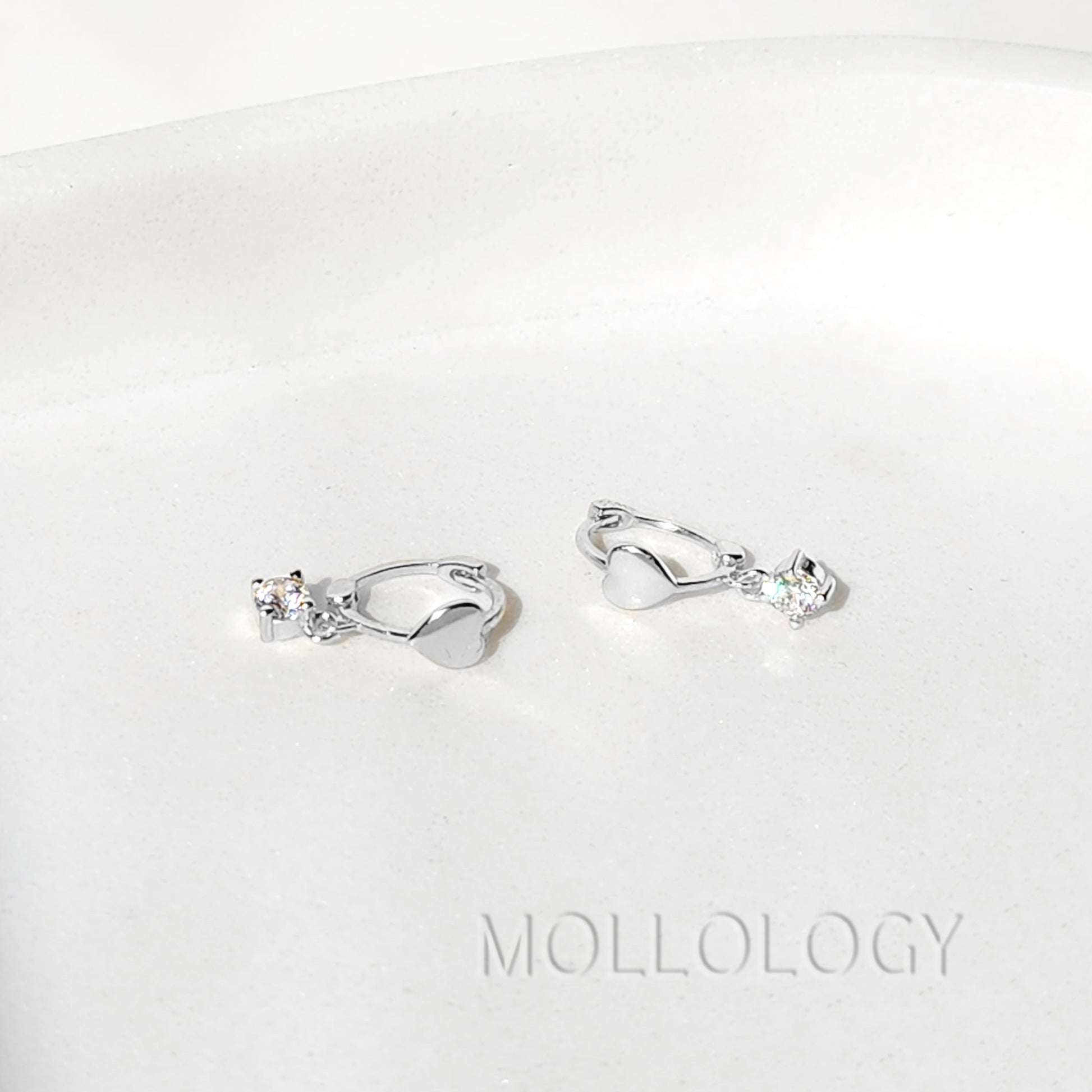Close up of 4mm cubic zirconia heart charm on gold huggie hoop