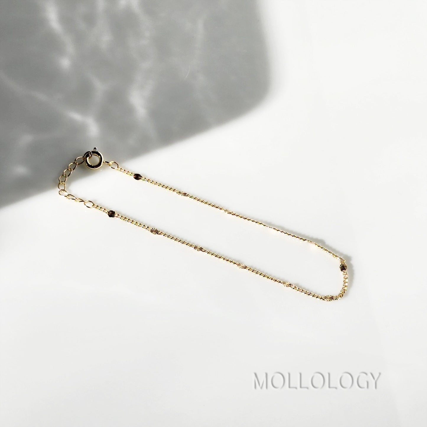 MiniClose-up of the 1-inch extension chain and lobster claw clasp on a dainty gold bracelet for an adjustable fit.