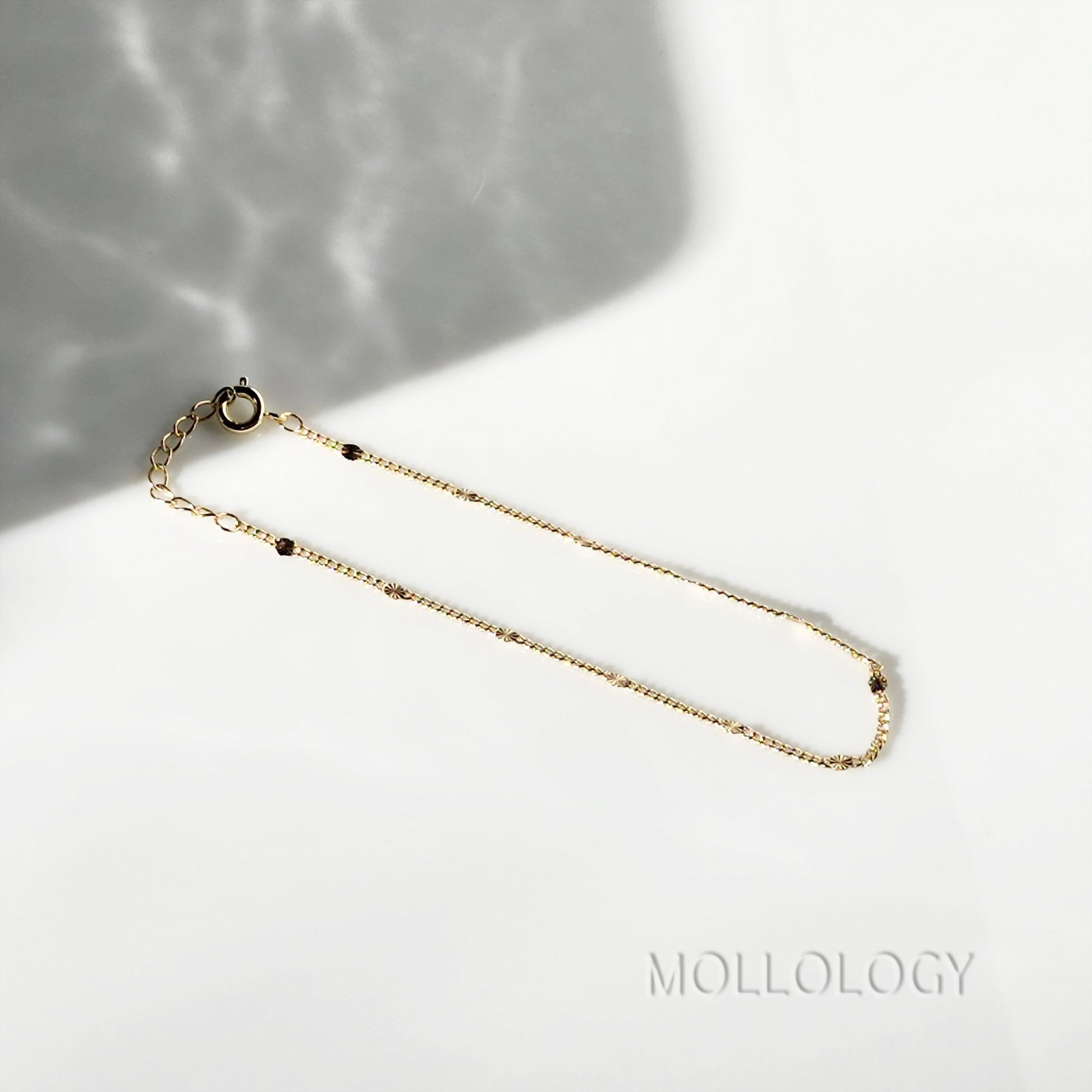 MiniClose-up of the 1-inch extension chain and lobster claw clasp on a dainty gold bracelet for an adjustable fit.