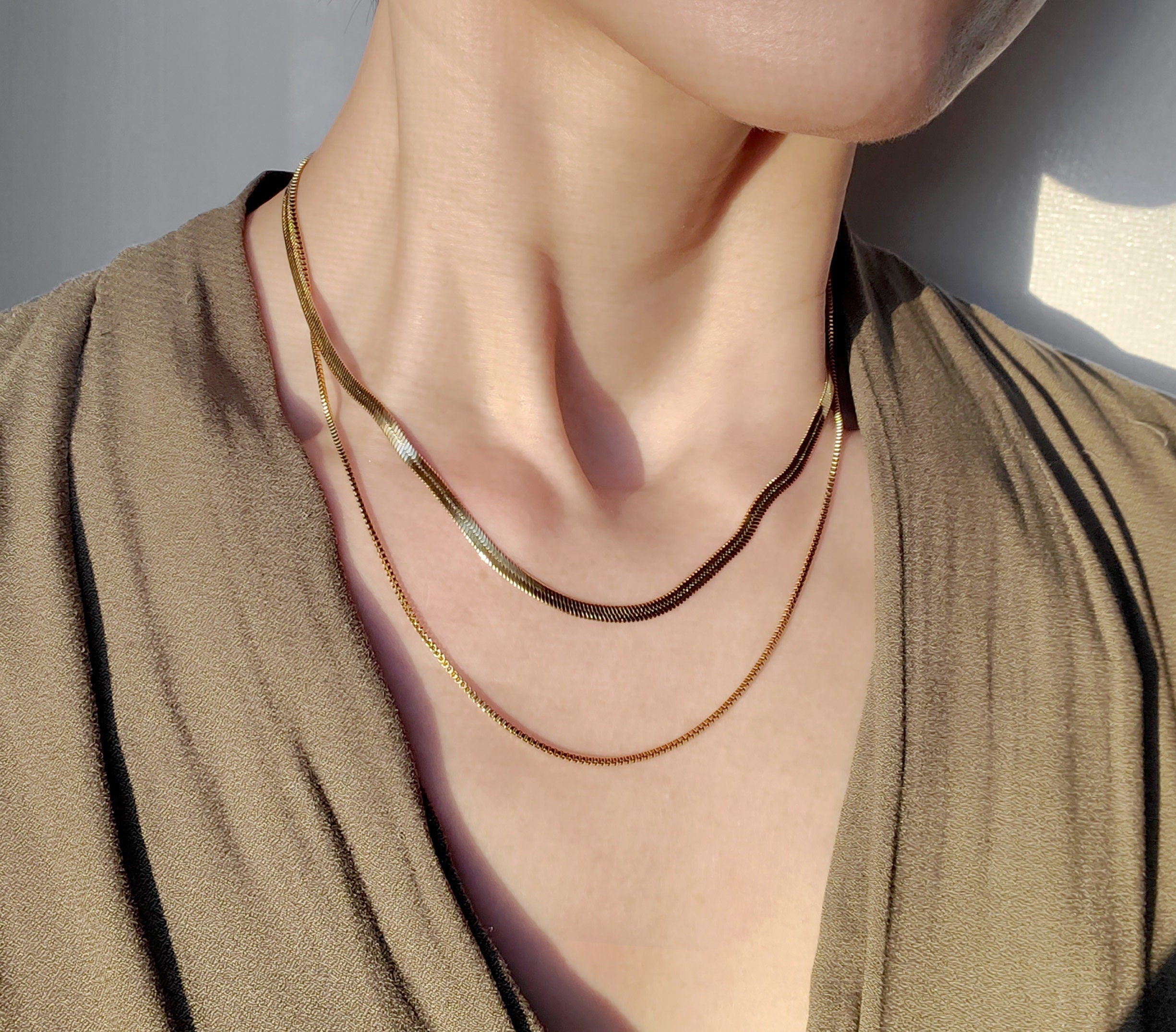 Layered gold necklace set featuring snake chain and box chain choker