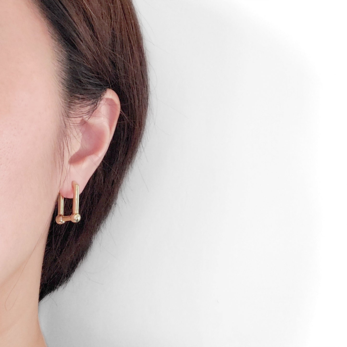 A set of gold-colored hoop earrings in various sizes, designed in the shape of hearts, displayed on a white surface.