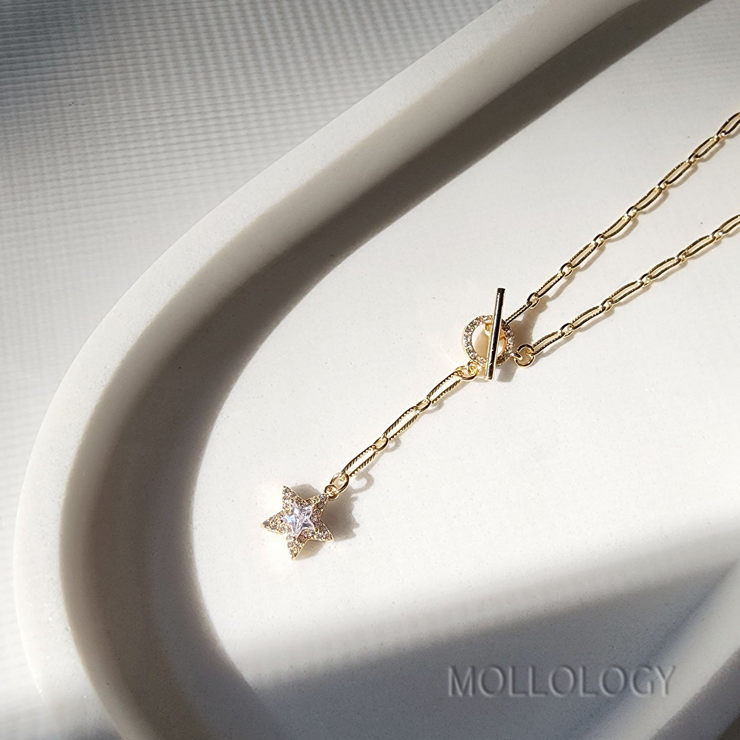  a gold chain link necklace with a star charm