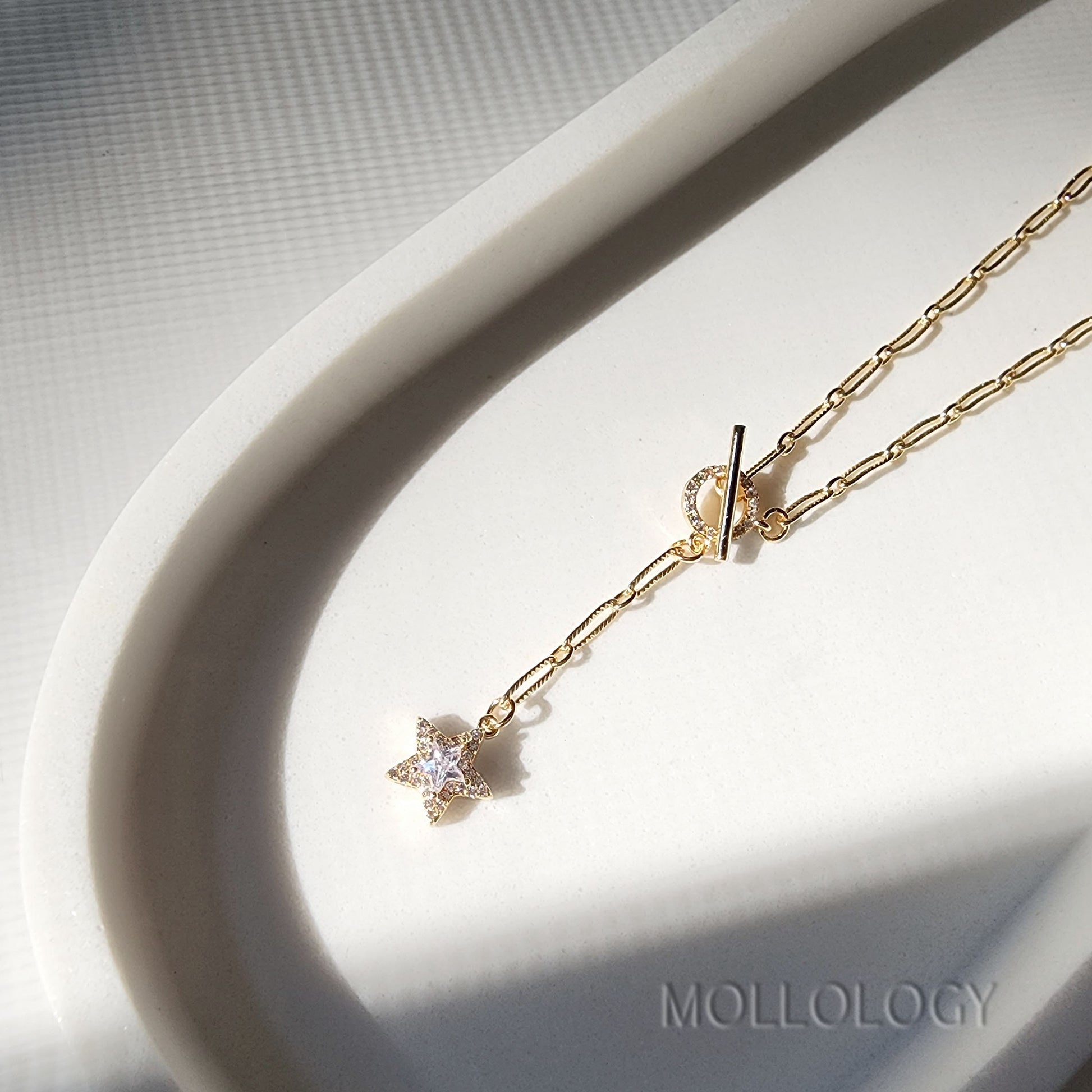  a gold chain link necklace with a star charm