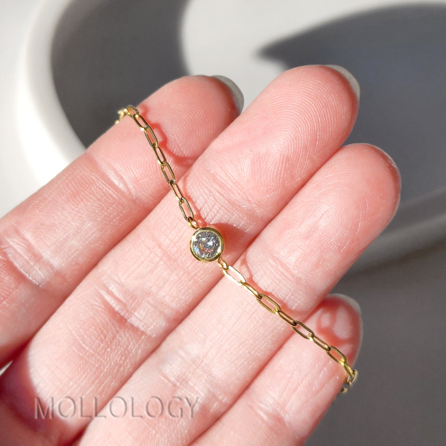 Close-up of 4mm bezel-set cubic zirconia on a gold paperclip chain.