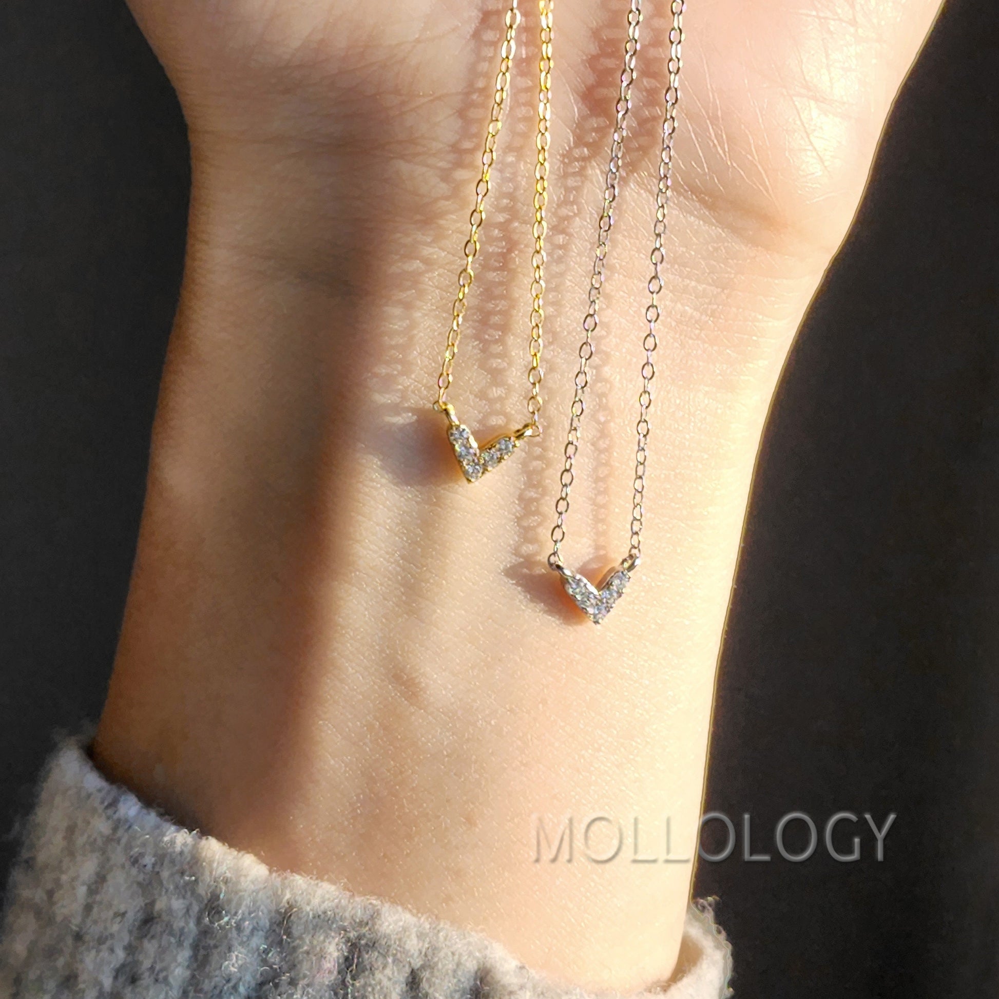 A dainty gold-colored heart-shaped necklace with small cubic zirconia accents, worn on a chain.