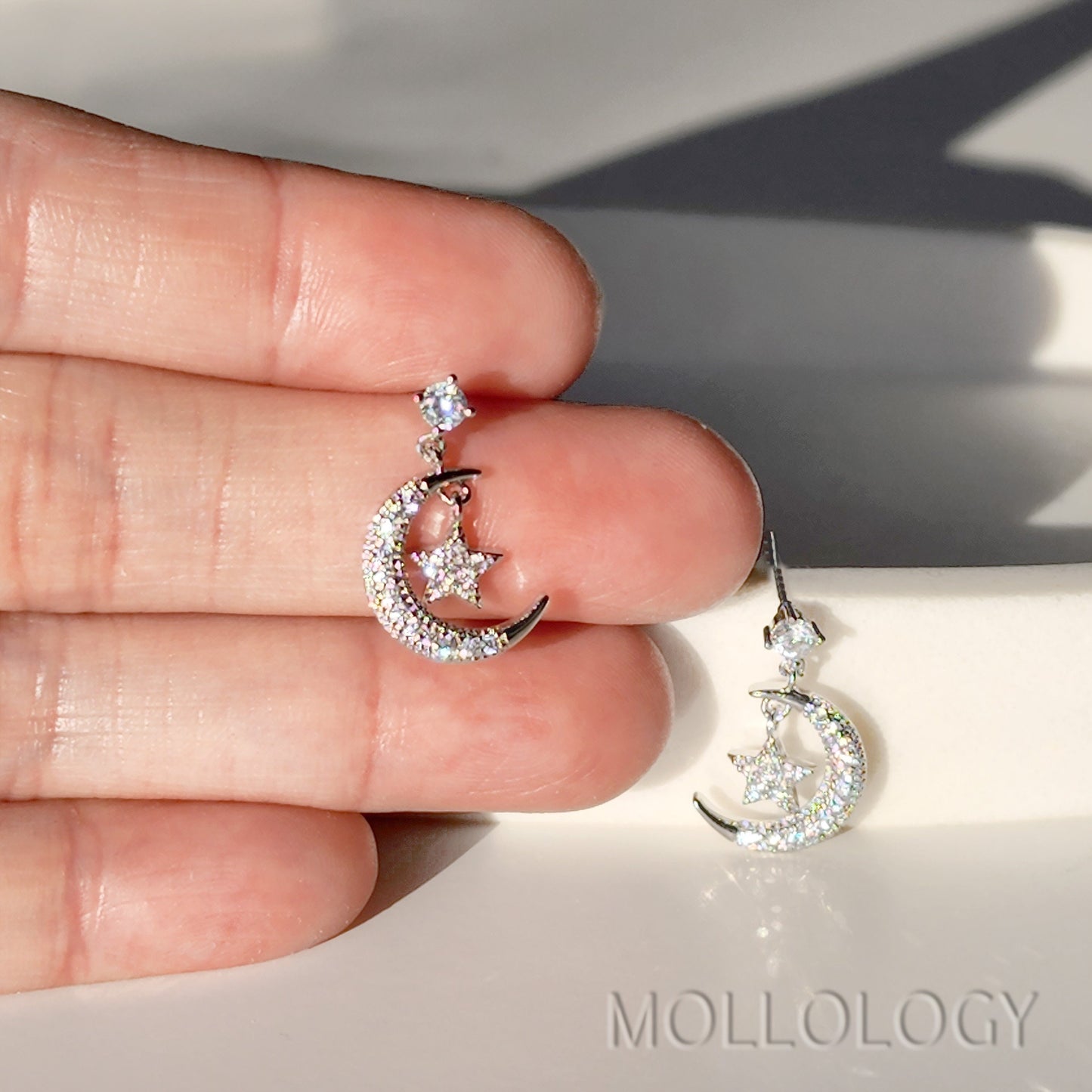 Moon and star CZ dangle earrings held in hand, dainty silver celestial jewelry product photo MOLLOLOGY.